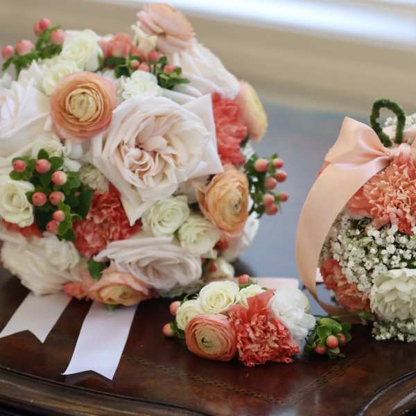 Two pastel floral bouquets with ribbon accents and a matching wrist corsage