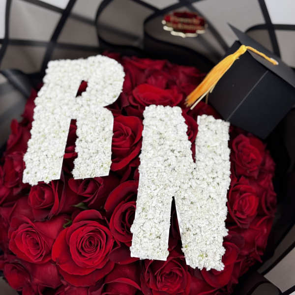 Red rose bouquet with white floral letters and a graduation cap topper