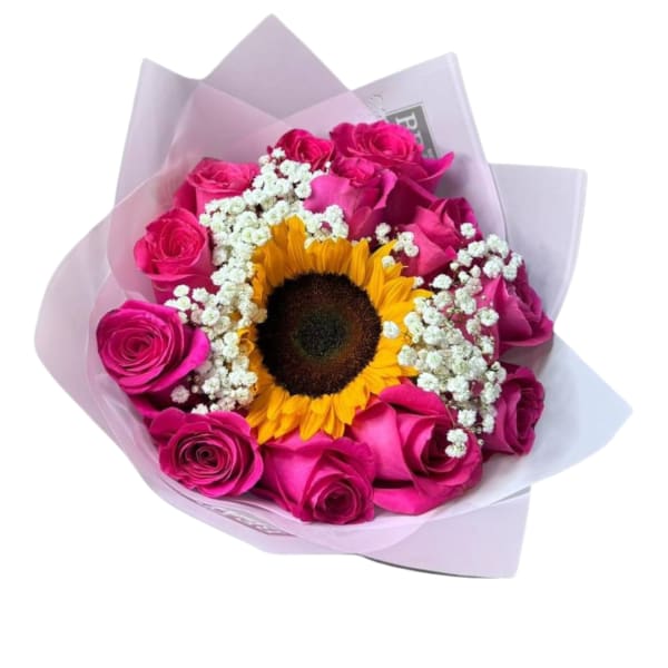 Hand-tied bouquet with a central sunflower, hot pink roses, and white filler flowers wrapped in pale pink paper
