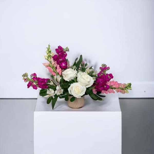 Arrangement of white roses and pink flowers in a small vase