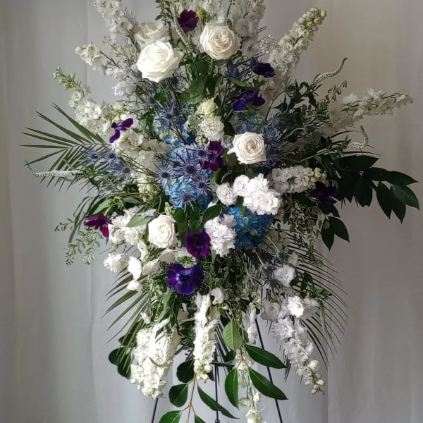Tall white and purple floral spray on a black stand