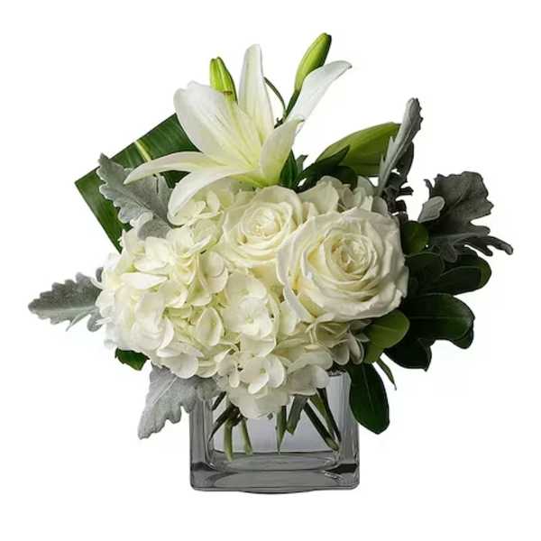 White lilies and roses arranged in a square glass vase