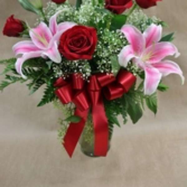 Bouquet of red roses and pink lilies with a red ribbon in a vase