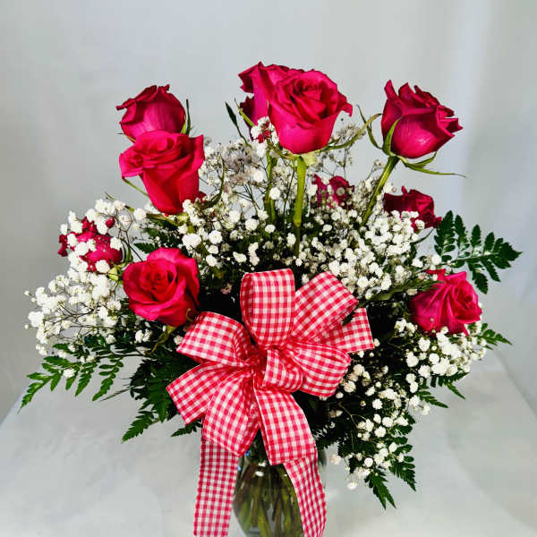 Pink roses with baby's breath in a glass vase and gingham bow