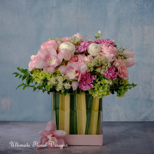 Pink and white mixed bouquet in a glass vase with a pink orchid at the base