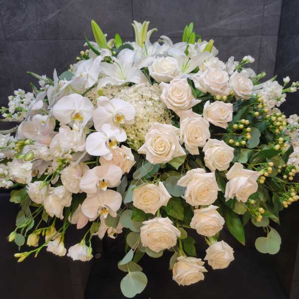 White roses and orchids arranged in a large floral spray