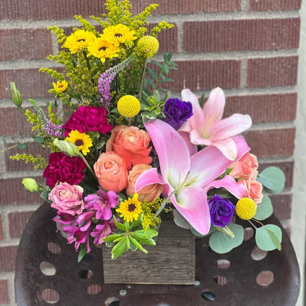 Mixed bouquet with pink lilies, roses, and yellow daisies in a wooden box