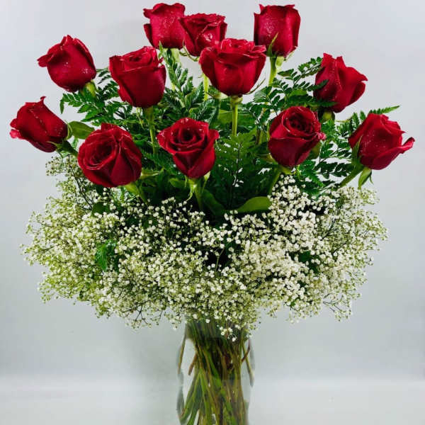 Red roses arranged in a clear glass vase with white baby's breath