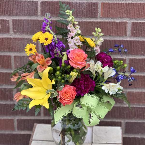 Mixed bouquet in a glass vase with yellow lilies and bright roses