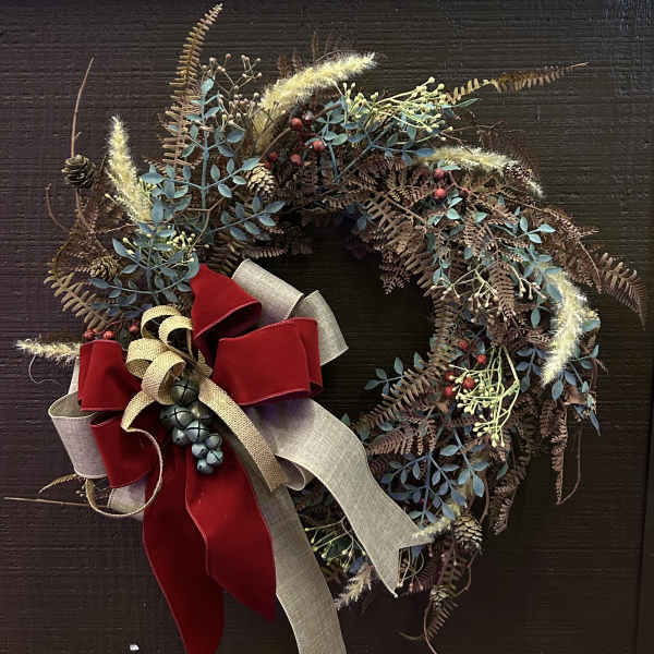 Rustic wreath with berries, pinecones, and a red ribbon bow