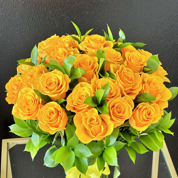 Bouquet of yellow roses with green foliage in a glass vase