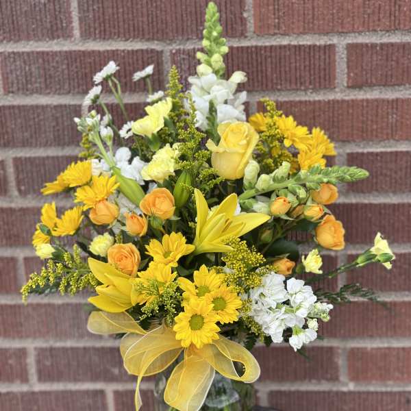 Yellow and white mixed bouquet in a glass vase with a yellow ribbon