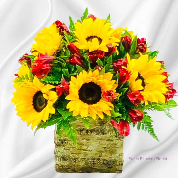 Sunflowers and red blooms arranged in a rustic square container