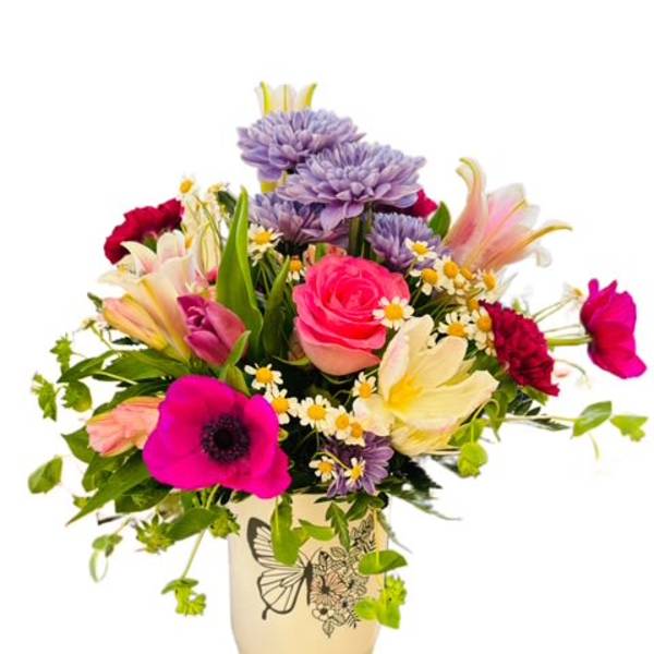 Colorful mixed bouquet in a cream vase with pink, purple, and white blooms