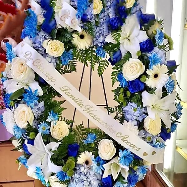 Large blue and white floral wreath with a memorial ribbon