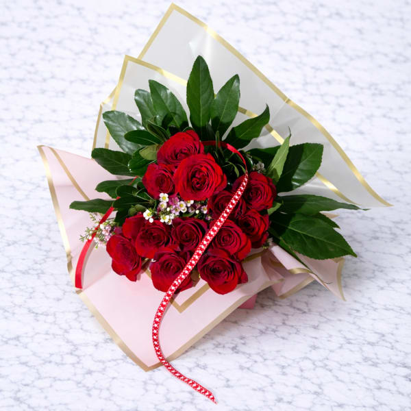 Bouquet of red roses with pink wrapping and a red ribbon