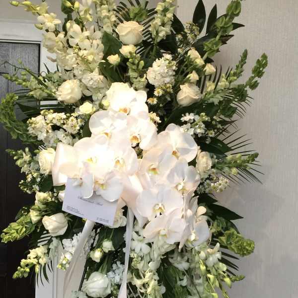 Tall white floral standing spray with orchids and roses on an easel