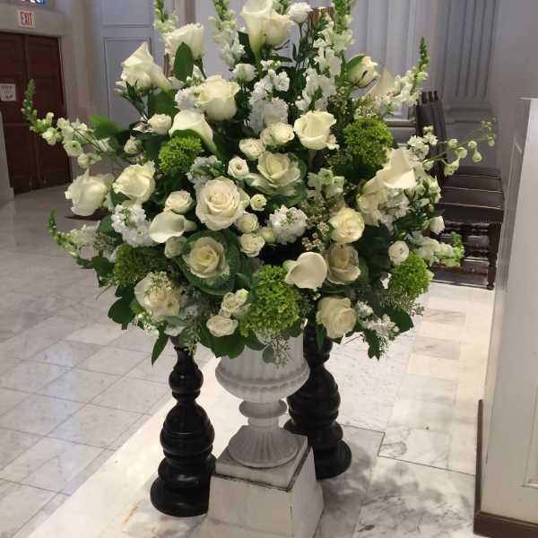 Large white floral arrangement in a pedestal urn