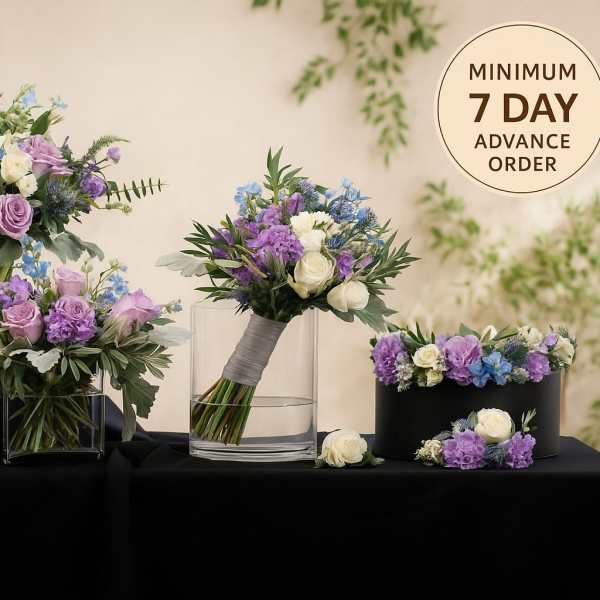 Wedding floral set with purple, white, and blue blooms in glass vases, a bouquet, and a floral crown on black cloth