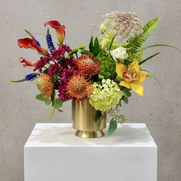 Colorful floral arrangement in a gold vase with calla lilies and mixed blooms