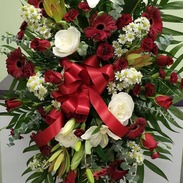 Large standing floral spray with red and white flowers and a red ribbon bow