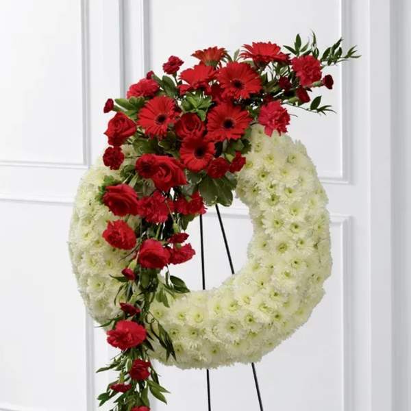 Red and white floral wreath on a black stand