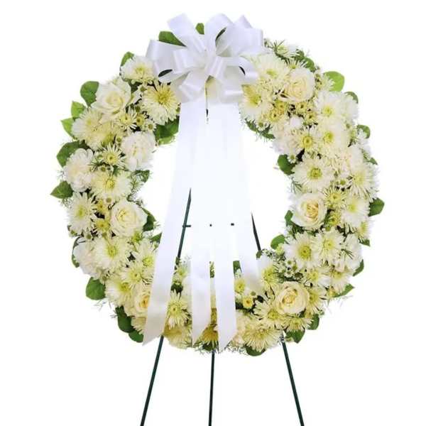 White floral wreath on a stand with a large white ribbon bow