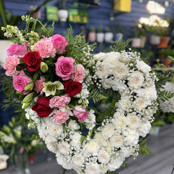 Heart-shaped floral arrangement with pink, red, and white roses