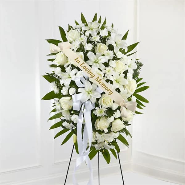 White sympathy wreath on an easel with a memorial ribbon