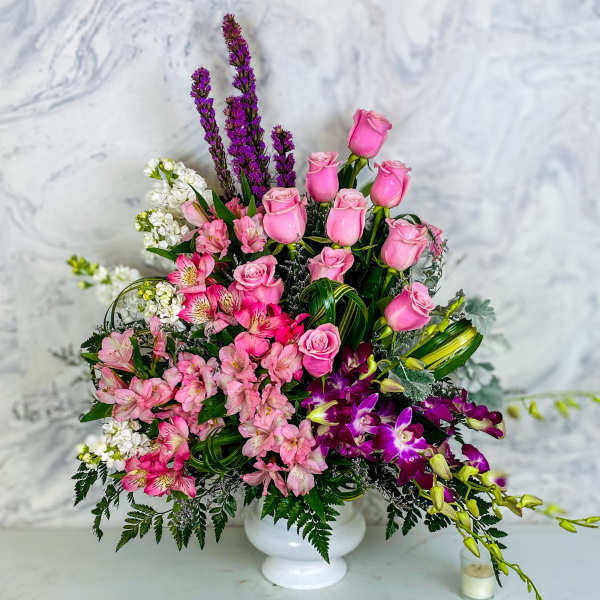 Pink roses and mixed blooms arranged in a white vase