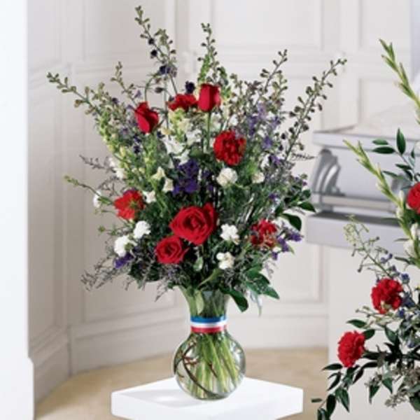 Tall bouquet of red, white, and purple flowers in a glass vase