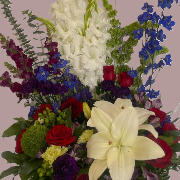 Tall mixed bouquet with white lilies, red roses, and blue flowers