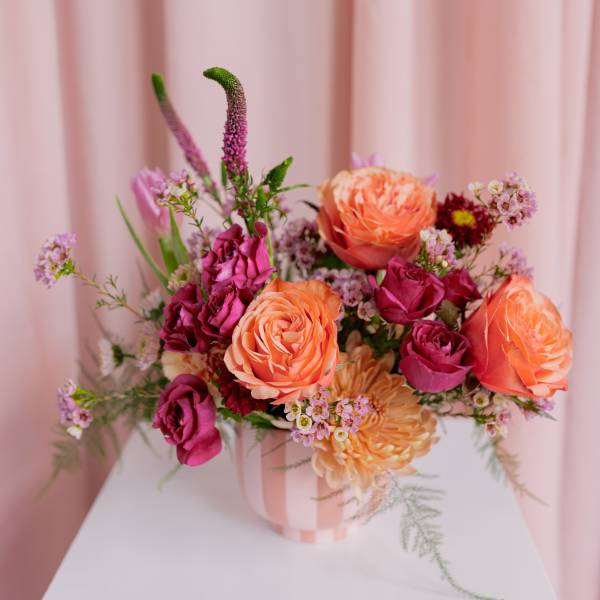 Pink and peach rose bouquet in a striped vase