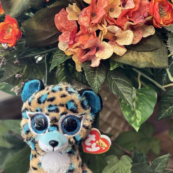 Plush leopard toy in front of an orange floral arrangement