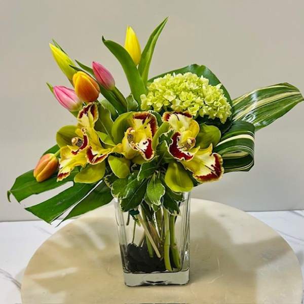 Tropical bouquet with tulips, orchids, and hydrangea in a clear vase