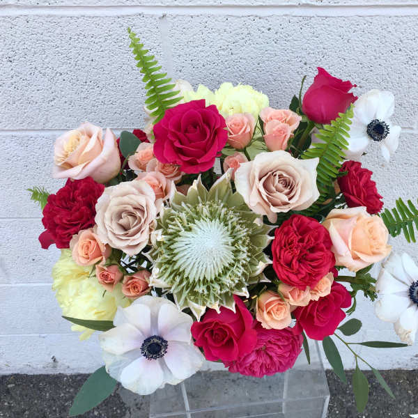 Mixed bouquet of roses and white anemones in a clear vase