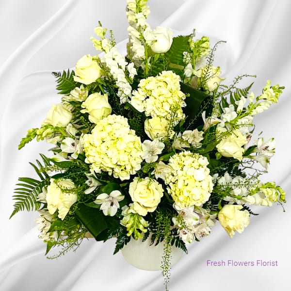 White floral arrangement in a round vase with roses and hydrangeas