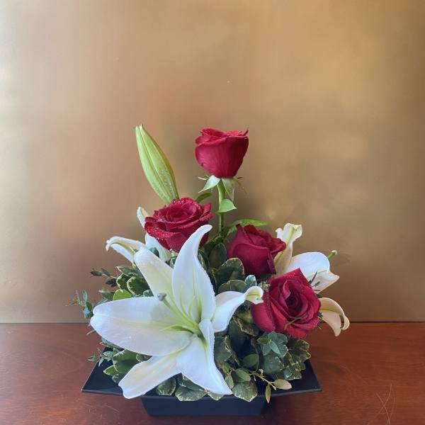 Red roses and white lilies arranged in a black rectangular container
