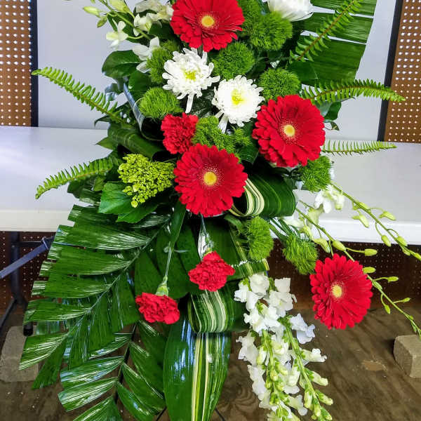 Tall floral spray with red and white flowers and large tropical leaves