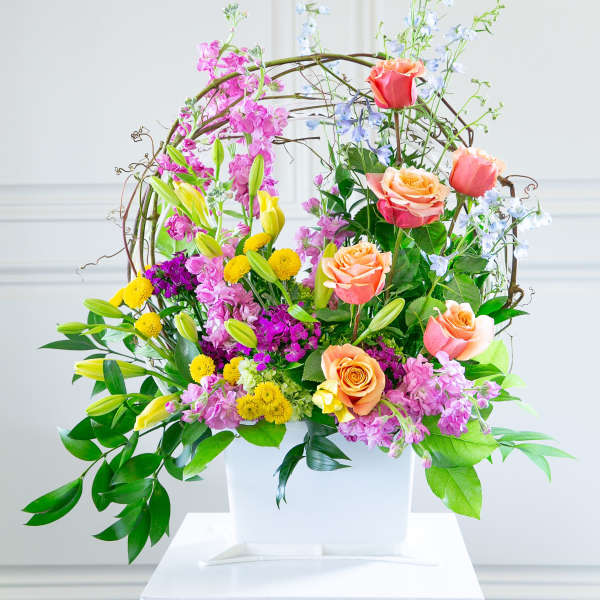 Colorful floral arrangement in a white container with roses and lilies