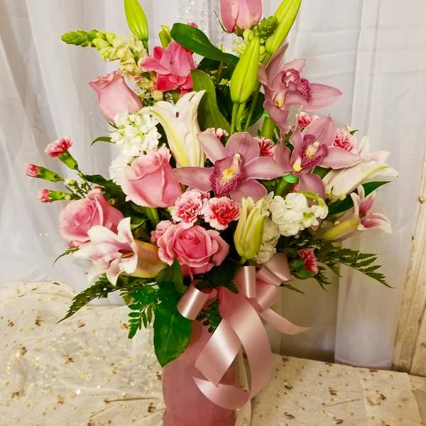 Pink and white floral arrangement in a pink vase with a ribbon bow