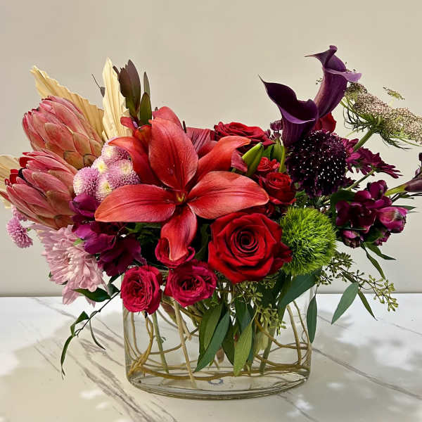 Mixed bouquet in a clear glass vase with red, pink, and purple flowers