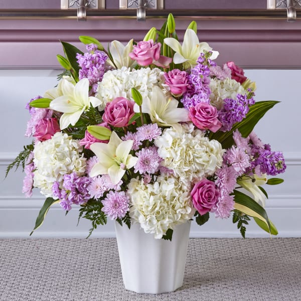 Pink roses and white lilies arranged in a white vase