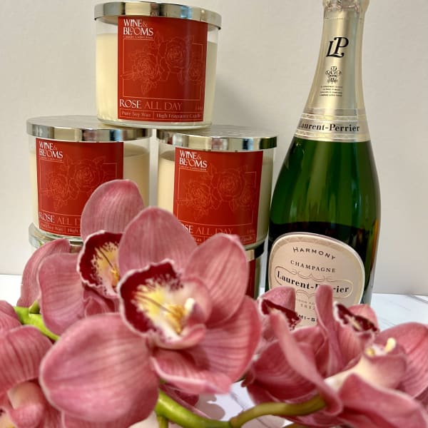 Pink orchids in front of rose-scented candles and a champagne bottle