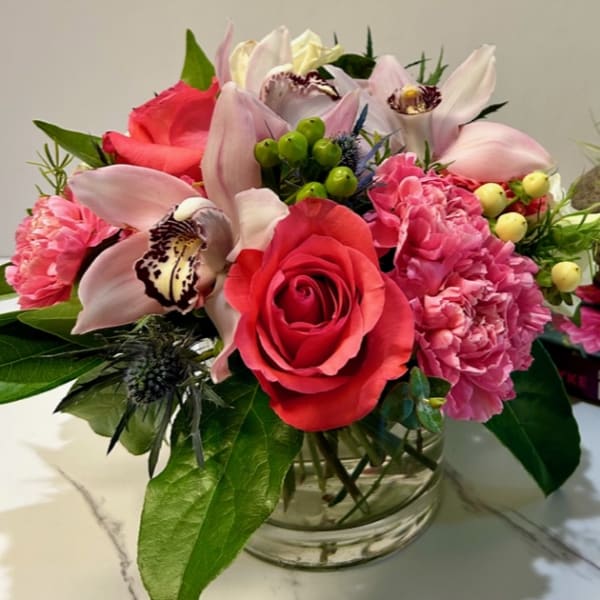 Bouquet of pink roses, orchids, and carnations in a glass vase