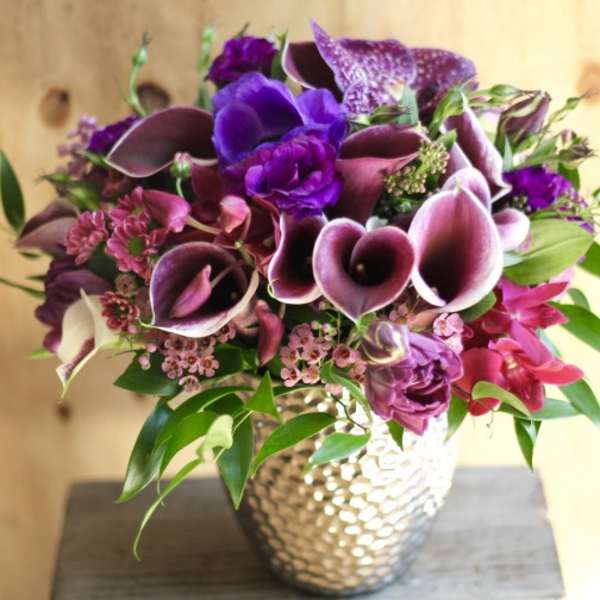 Purple and pink floral arrangement in a textured silver vase
