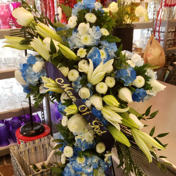 Large blue and white funeral spray with lilies and roses on a stand