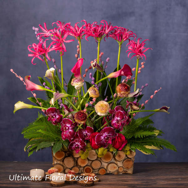 Tall floral arrangement with pink lilies, orchids, and calla lilies in a log container