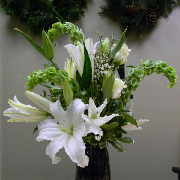 White lilies arranged in a tall black vase