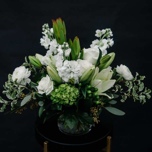 White floral arrangement with lilies and roses in a glass vase
